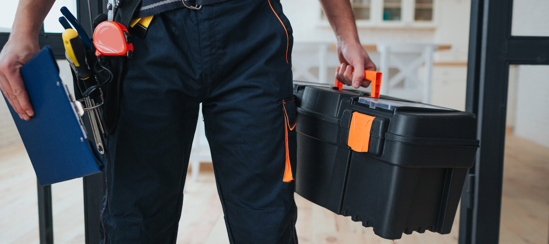 A contractor carrying a toolbox and clipboard.